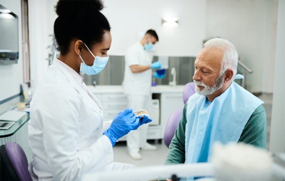 A dentist explaining denture candidacy to an older man