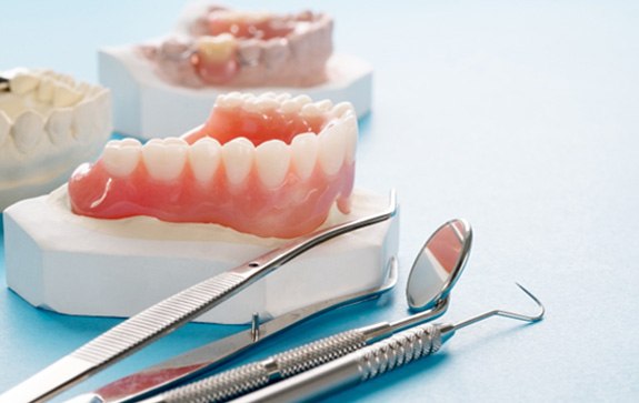 A closeup of a full denture against a blue background 