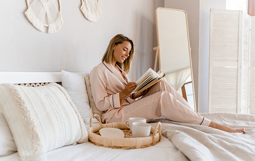 Woman sitting on bed, relaxing at home