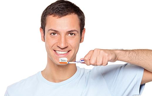 Man using toothbrush to clean his dental implants in Goodyear