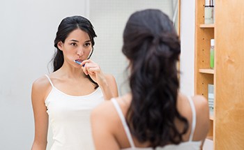 Woman practicing dental implant care in Goodyear by brushing teeth