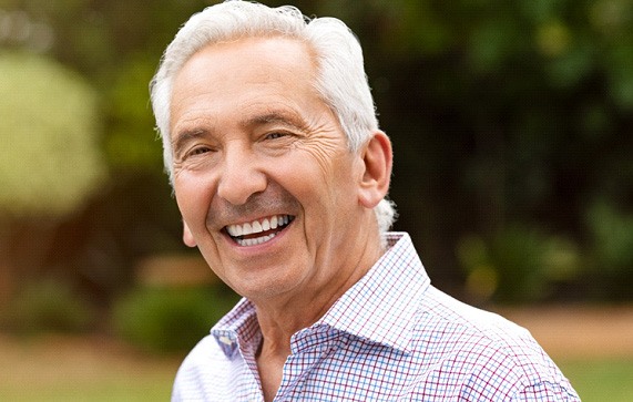 Senior man smiling outside with button-up shirt