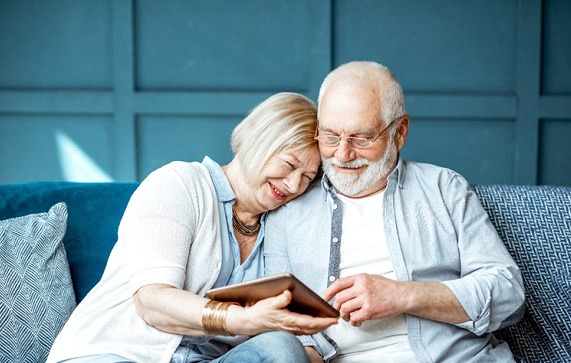 Senior man and woman on couch looking at tablet