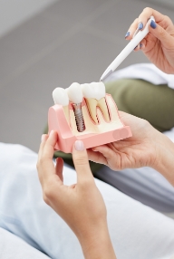Dentist and patient looking at a dental implant model