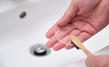 Patient using toothbrush to clean aligner