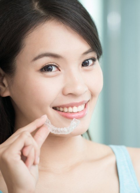 Smiling woman holding an Invisalign tray