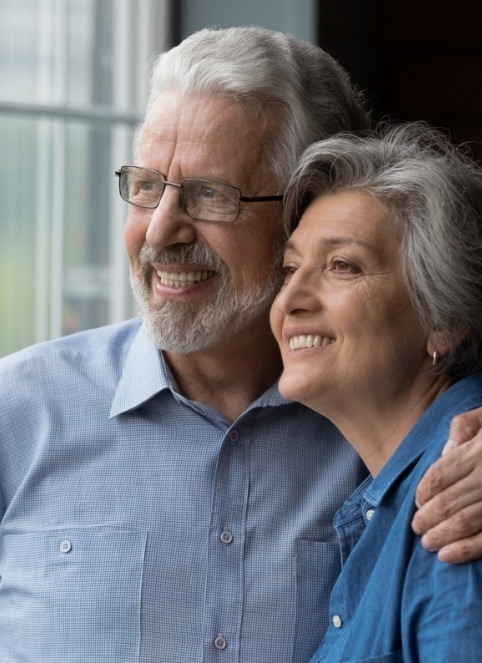 Man and woman smiling after replacing missing teeth