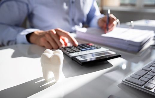 Man calculating costs at a desk with a large model tooth