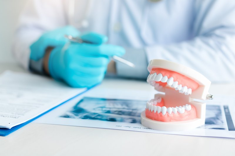 A closeup of a denture sitting on a table near a dentist